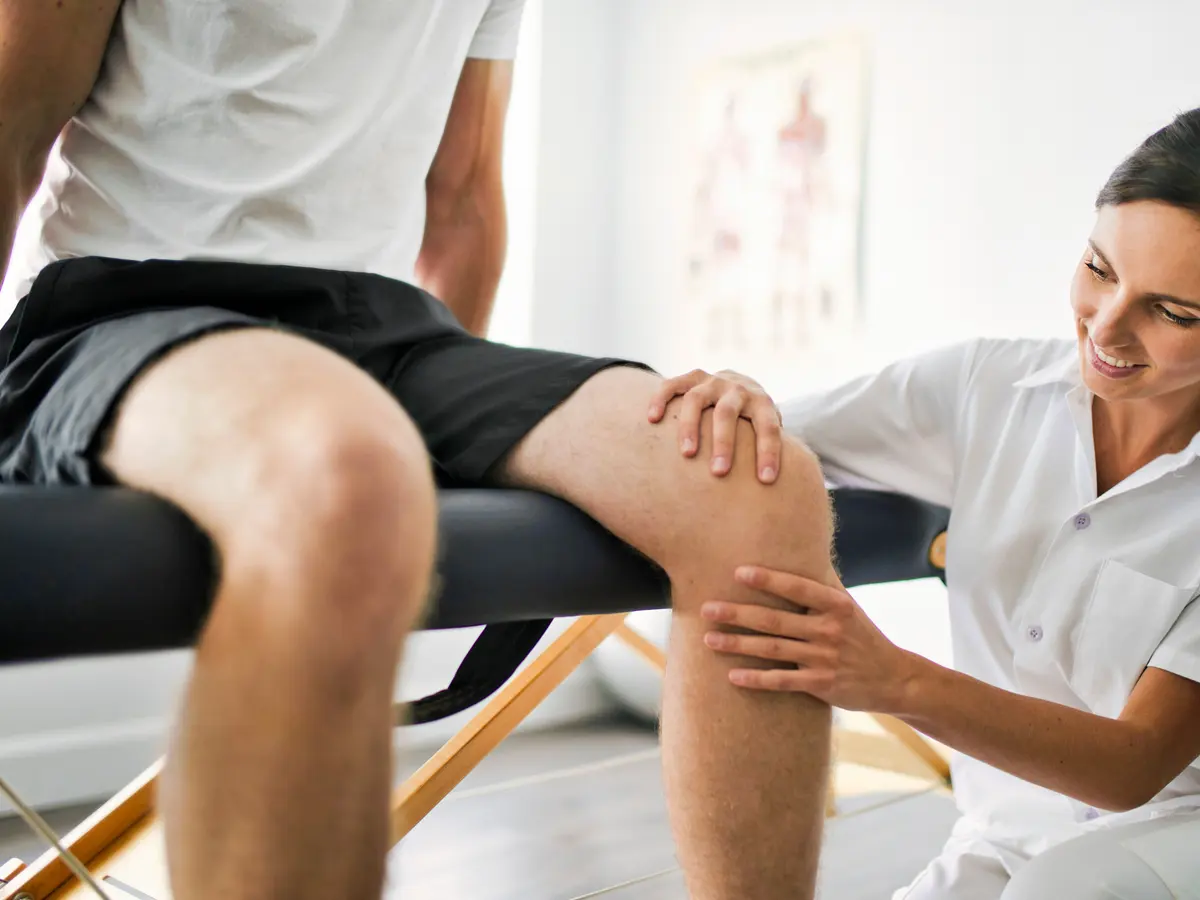 A doctor examining a patient's knee during an office visit