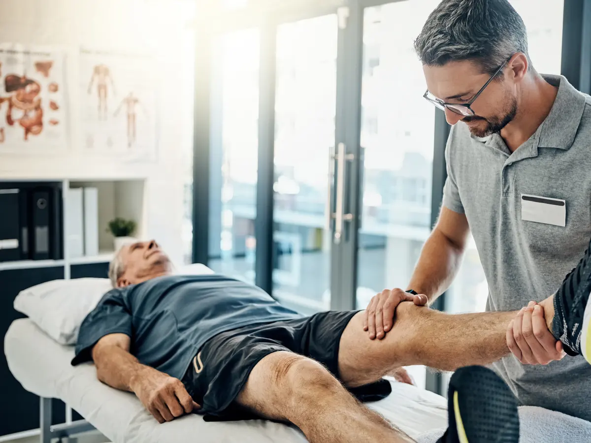 Physical therapist stretching an injured patient's leg during a rehab session
