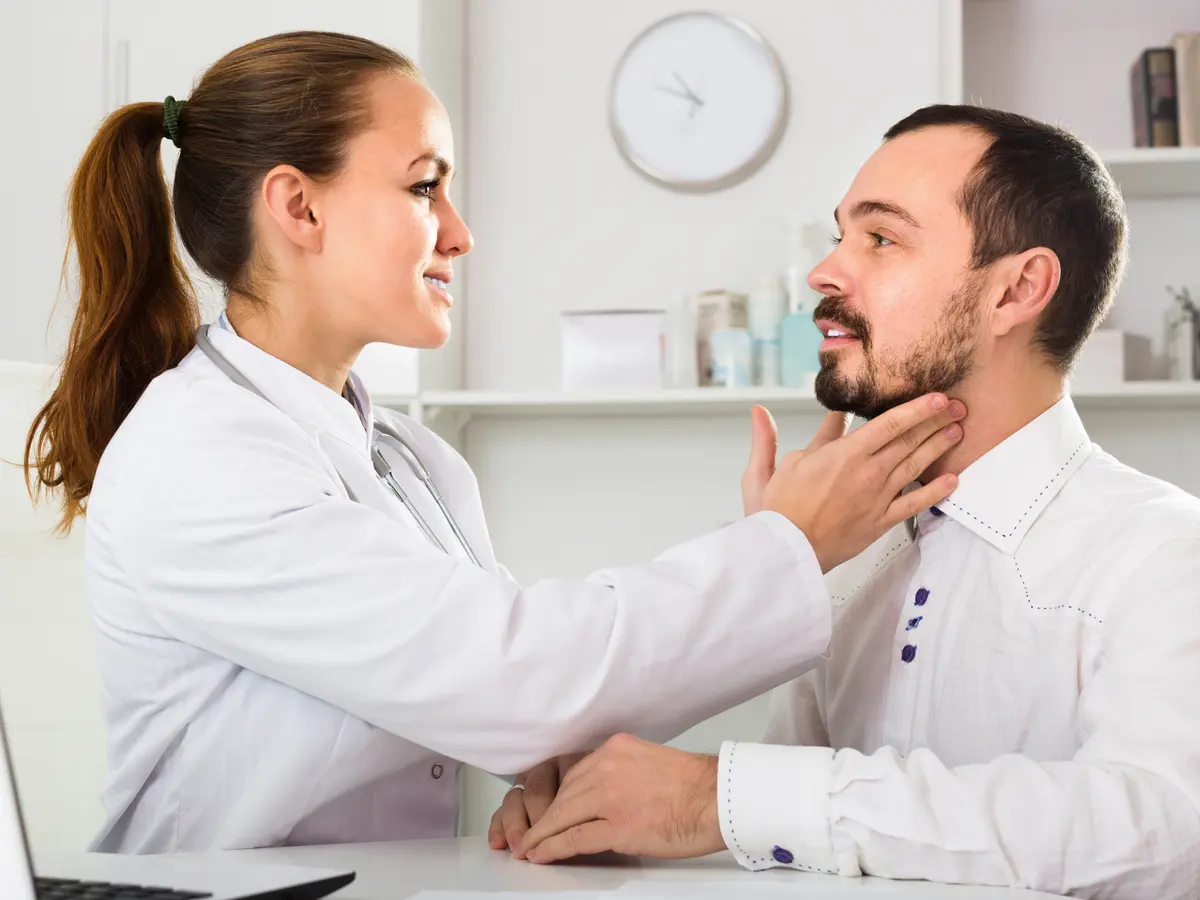 Doctor checking a patient's neck and throat during a primary care visit
